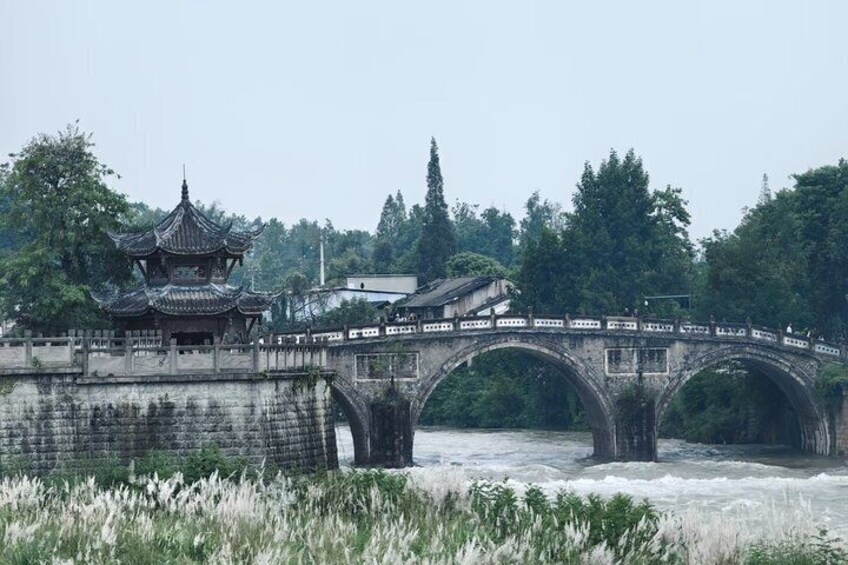 Un puente chino tradicional con múltiples arcos sobre un río, rodeado de exuberante vegetación y un edificio de estilo pagoda. 4