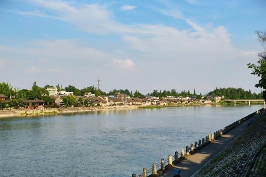 Un río con una pasarela a la derecha, edificios a lo largo de la orilla y un cielo despejado. 2