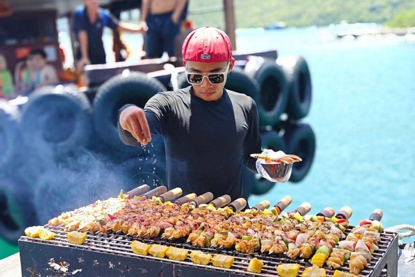 A person grilling various meats and vegetables on a barbecue. 2
