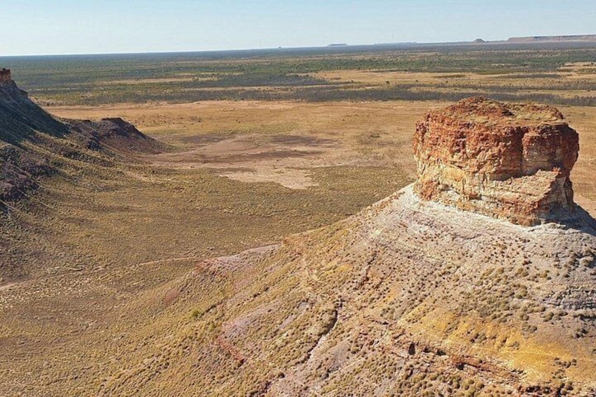 A desert landscape with a prominent rock formation and a flat valley. 2