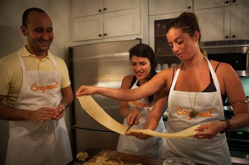 Three people wearing aprons with the word 'Cozmeal' on them, preparing food in a kitchen. 3