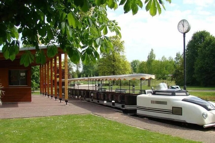 A train station with a modern train, a clock, and a covered waiting area. 3