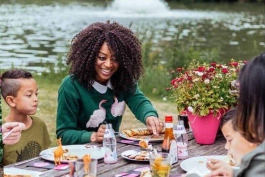 A person sitting at a table with food, outdoors near a body of water. 2