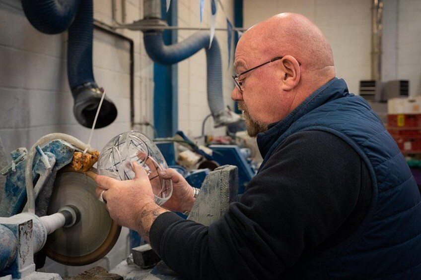 A person working with a large circular machine, possibly a lathe, in a workshop environment. 2
