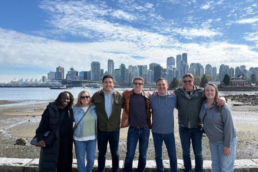 A group of people standing on a beach with a city skyline in the background. 2