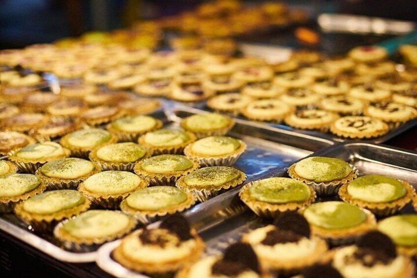 A display of various pastries, including green-topped and chocolate-topped items, arranged on trays. 3