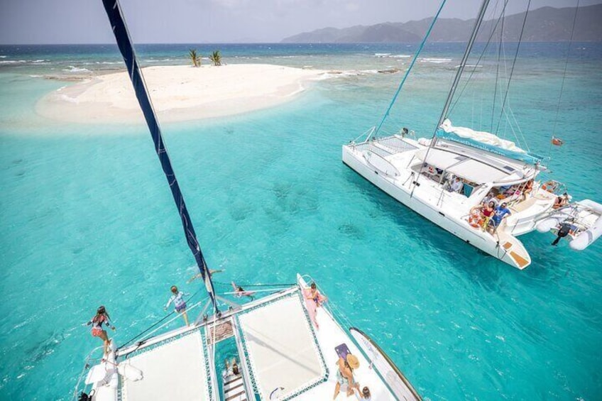 A sailboat anchored near a white sandy beach surrounded by turquoise waters. 4