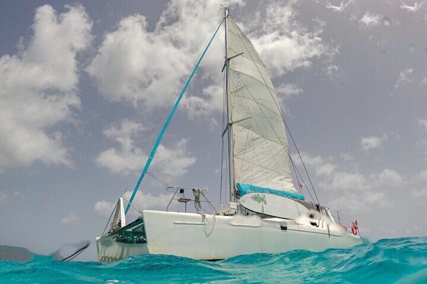 A white catamaran sailing on turquoise waters with a clear sky and scattered clouds. 4