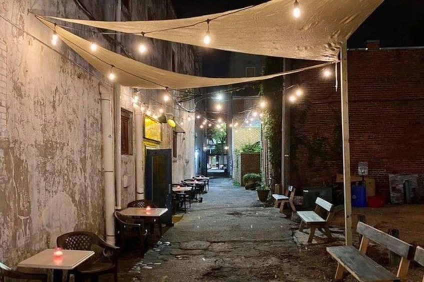 An outdoor dining area with tables and chairs under string lights. 1
