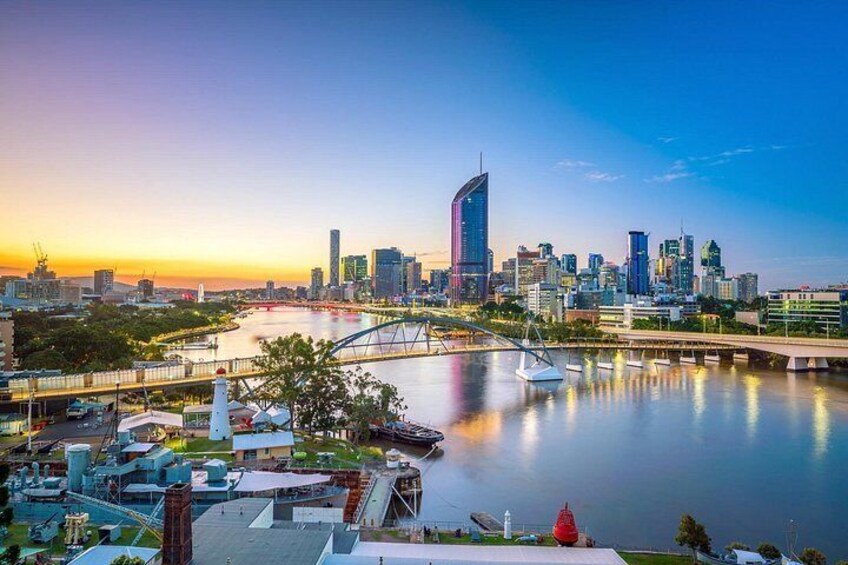 A city skyline at sunset, a river, a bridge, and a park with boats. 3