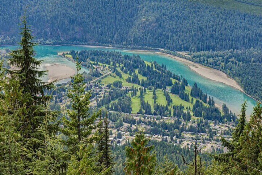 Un paisaje costero con una bahía turquesa, un bosque denso y un pequeño pueblo. 1