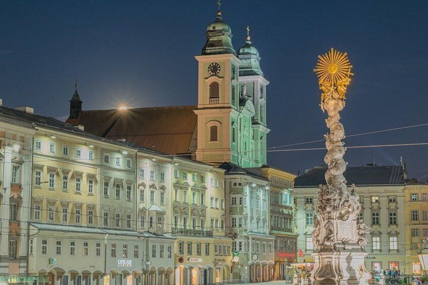 A historic building with a clock tower and a statue. 4