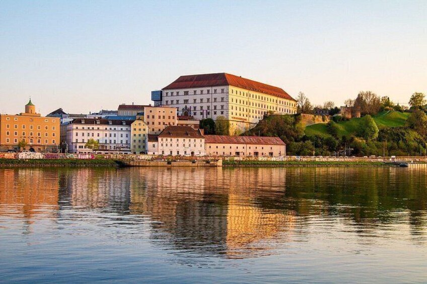 A riverside view of historic buildings with a prominent white building with a red roof. 5