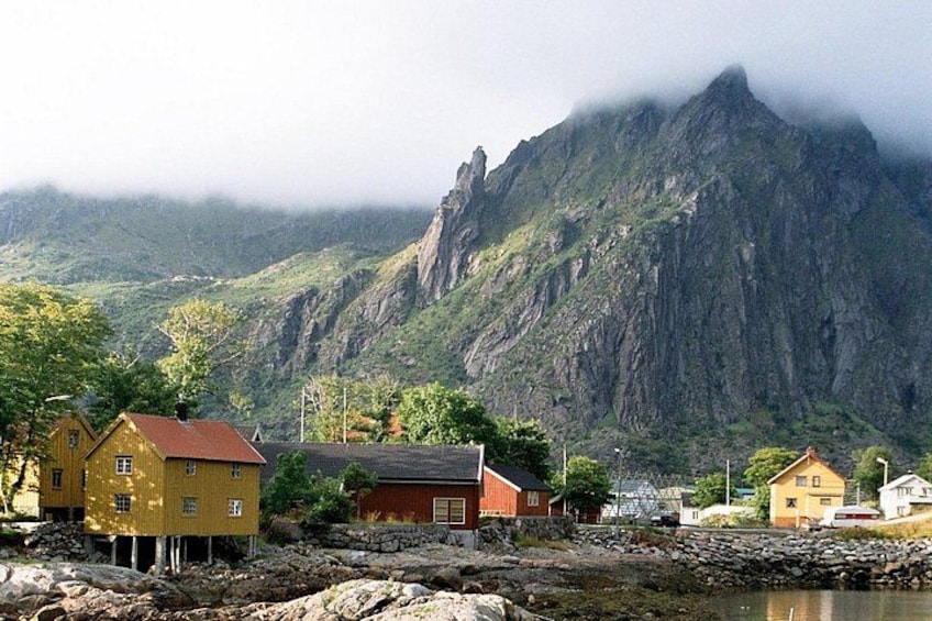 Ein Küstendorf mit Häusern in der Nähe einer felsigen Küstenlinie und einem Berg im Hintergrund. 1