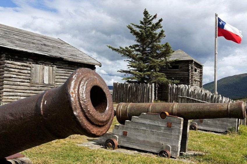 A large cannon in front of a wooden building with a flag. 4