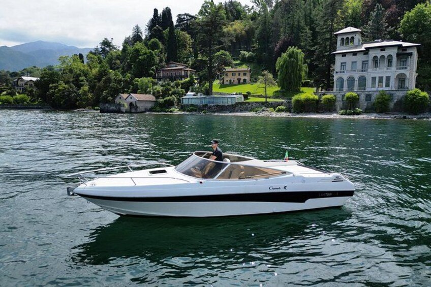 A white speedboat on calm water with a backdrop of houses and trees. 3
