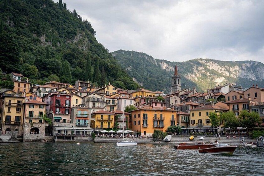 Eine Stadt am See mit bunten Häusern, einem Kirchturm und Booten auf dem Wasser. 2
