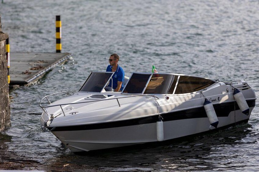 Ein kleines Motorboot mit einer Person an Bord, vertäut an einem Steg. 1