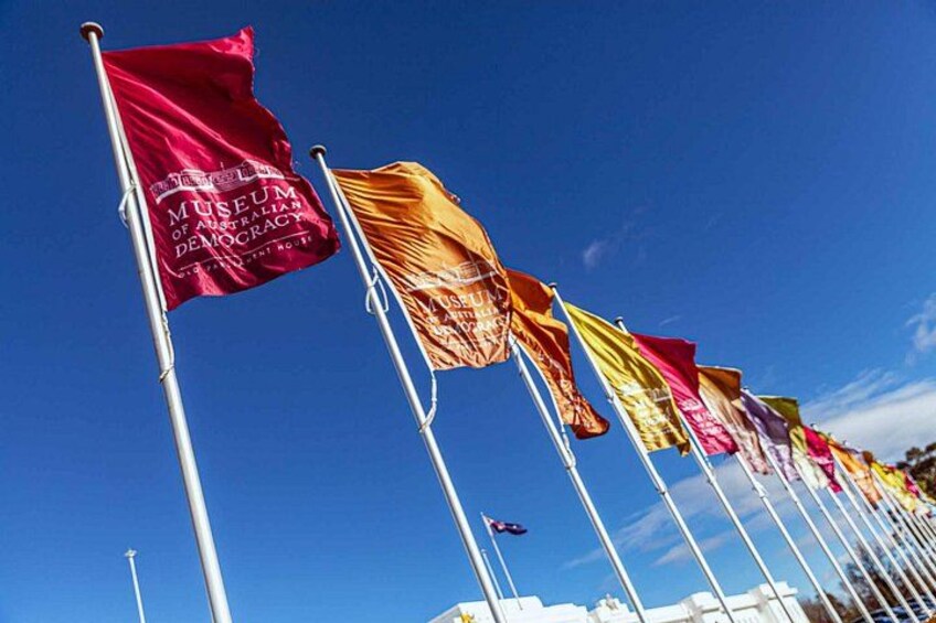 A row of flags on flagpoles against a clear blue sky. 5