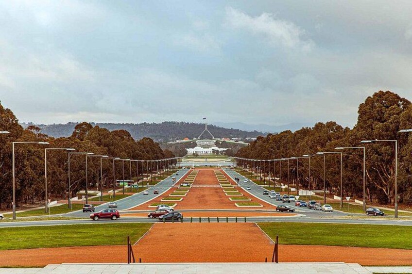 A wide road with multiple lanes, trees lining the sides, and a distant landmark. 3