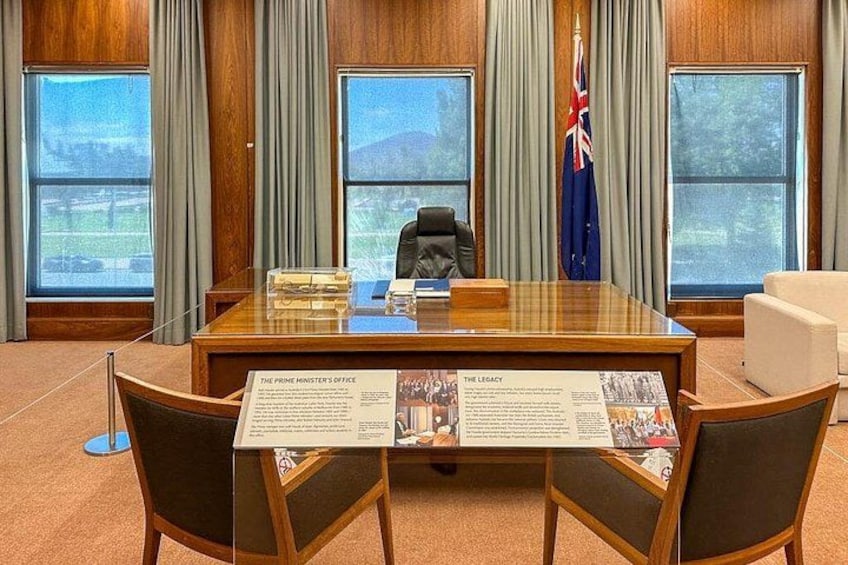 A conference room with a wooden table, chairs, a flag, and informational displays. 4
