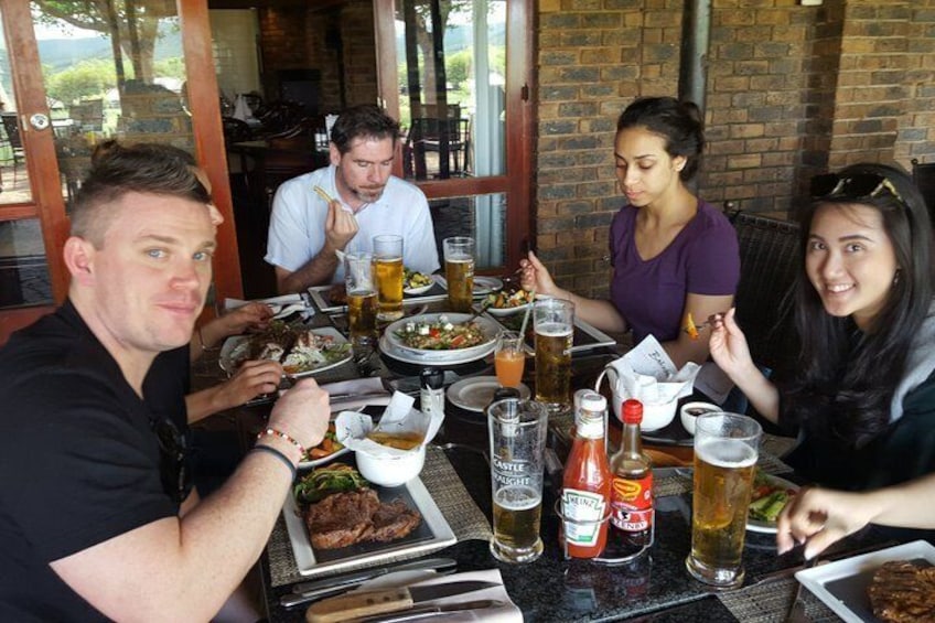 A group of people dining at an outdoor restaurant with various dishes and drinks on the table. 4