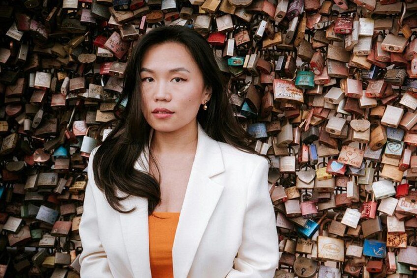 A person standing in front of a wall covered with numerous padlocks. 1