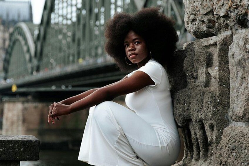 A person sitting on a stone ledge with a bridge in the background. 5