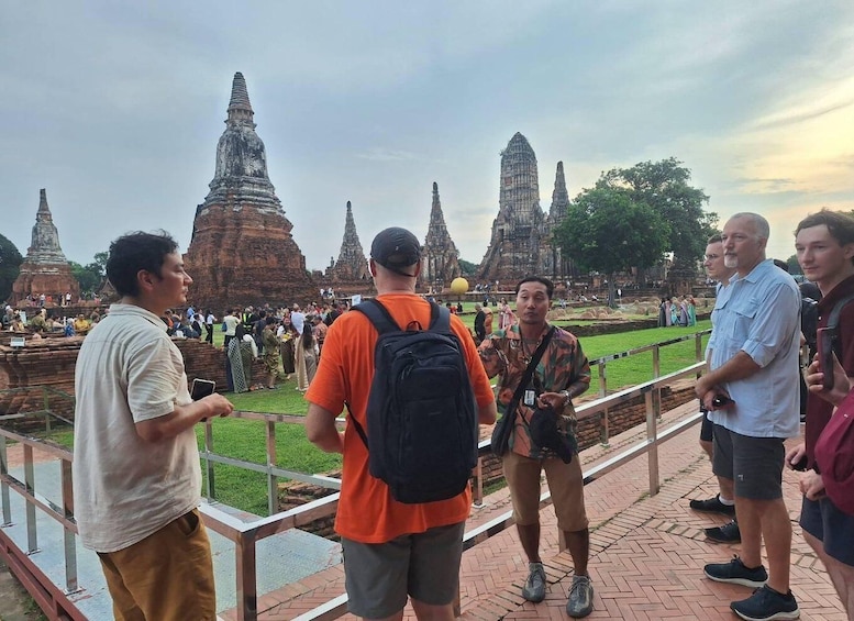 A group of tourists at a temple complex with multiple tall, tiered structures. 3