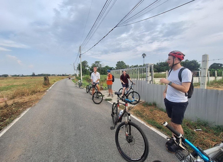 A paved path with cyclists and a person standing by a bicycle. 5
