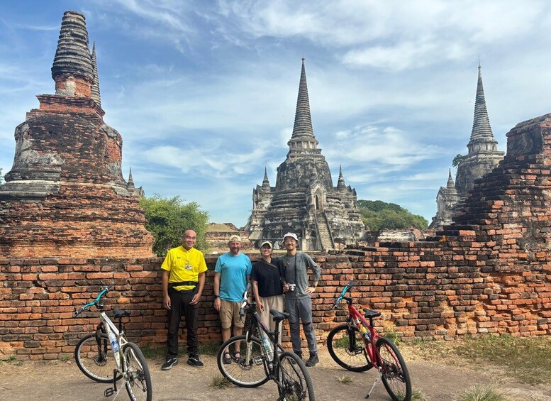 A group of people standing in front of ancient brick ruins with multiple conical structures. 2