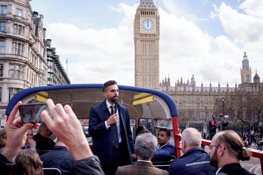A man speaking to a crowd from a bus in front of the Big Ben clock tower. 5