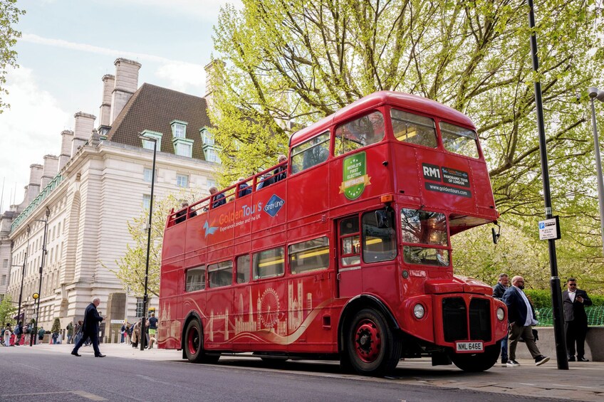 A red double-decker bus with 'Golden Tour' and 'RayLine' logos, parked on a city street. 1