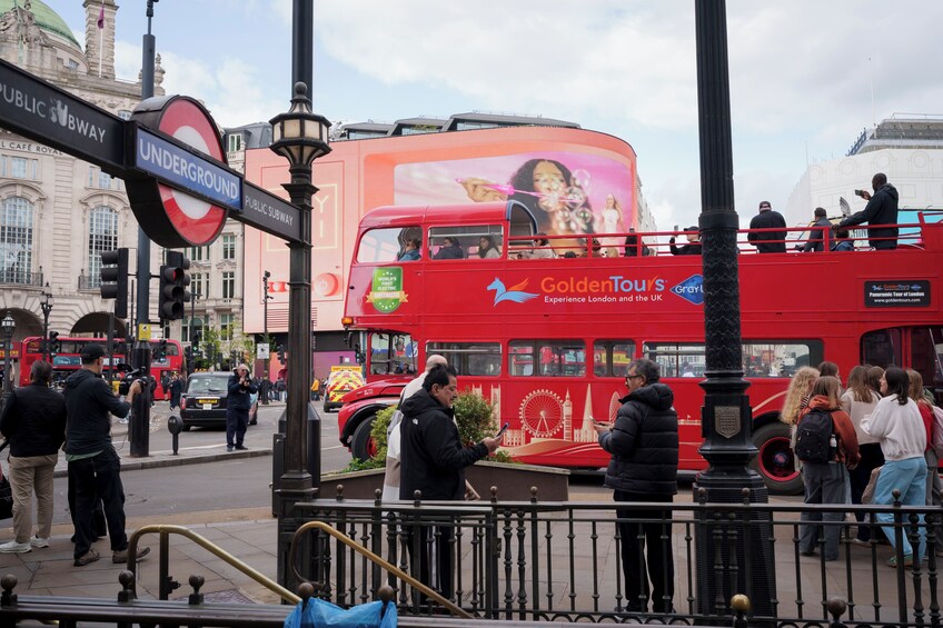 A red double-decker bus with 'Golden Tours' advertising, a 'Public Subway' sign, and a 'World's Best Electric' sign. 3