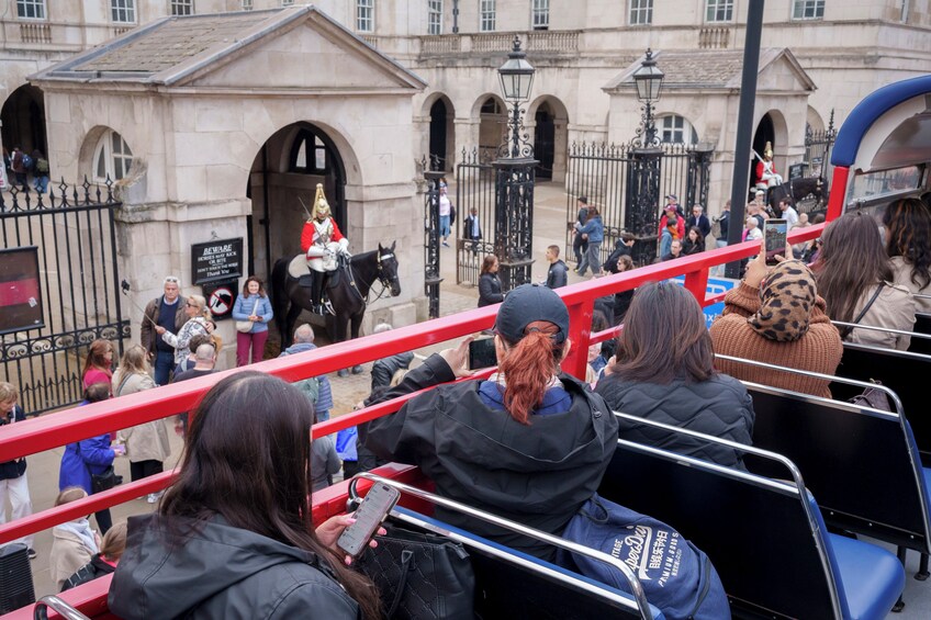 A crowd of people on a red bridge, with a horse and rider in the background. 4