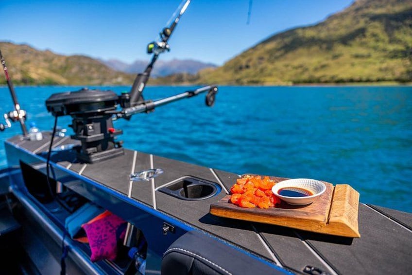 Un bote con cañas de pescar, una tabla de madera con pescado y un bol de salsa. 1