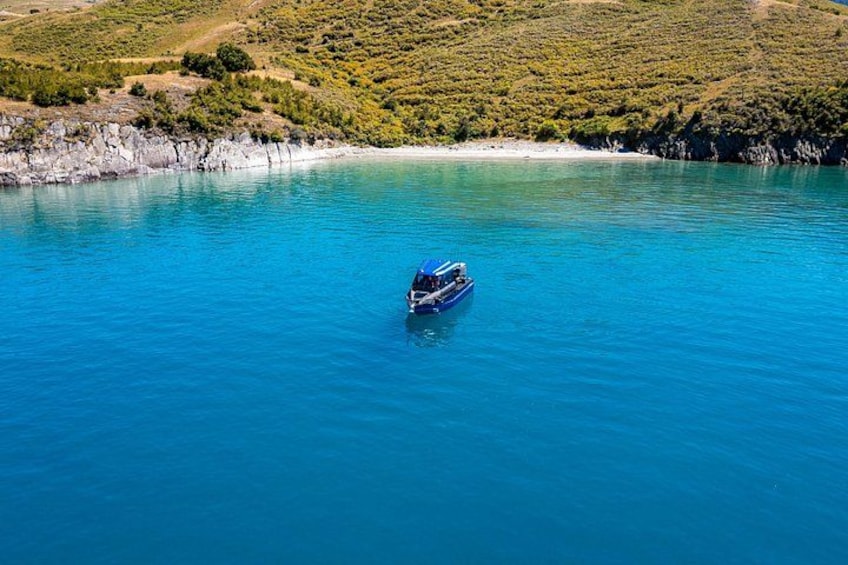 Un bote en un lago turquesa rodeado de colinas. 5