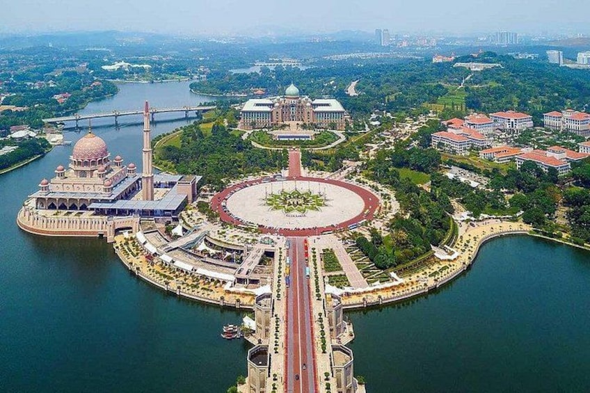 A large circular park with a central monument, surrounded by water and connected to a cityscape with buildings and a river. 2