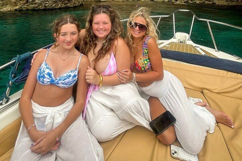Tres personas en un bote con una costa rocosa al fondo. 3