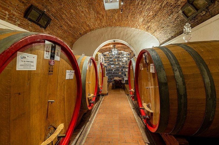 A wine cellar with wooden barrels and a brick floor. 2