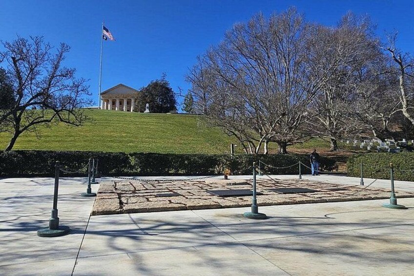 A paved plaza with a flagpole, a building in the background, and leafless trees. 3
