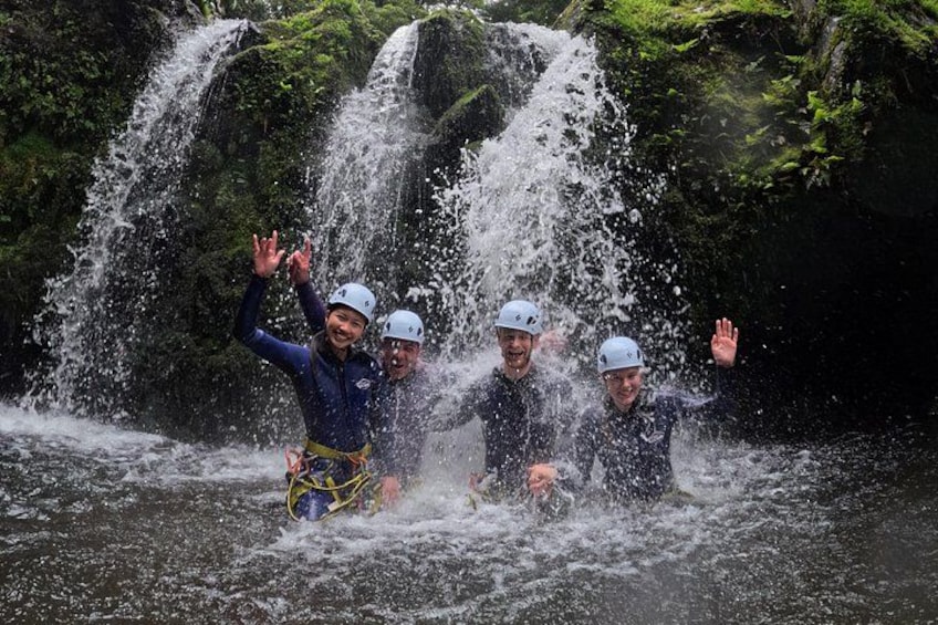 Un grupo de personas en un río con una cascada al fondo. 1