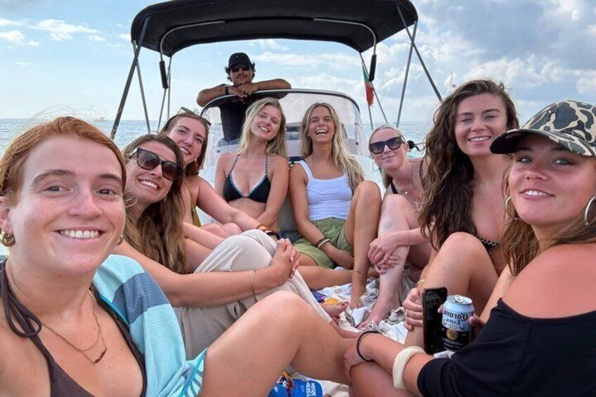 A group of people on a boat with a canopy, some holding drinks, and a clear sky in the background. 5