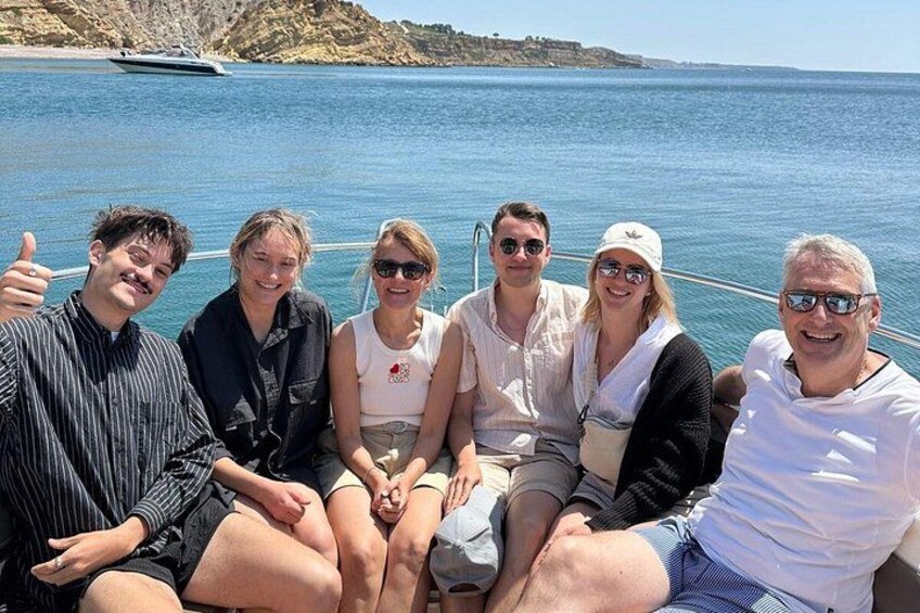A group of people on a boat with a body of water and a distant shoreline in the background. 3