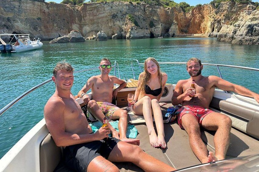 A group of people on a boat in a body of water with rocky cliffs in the background. 4