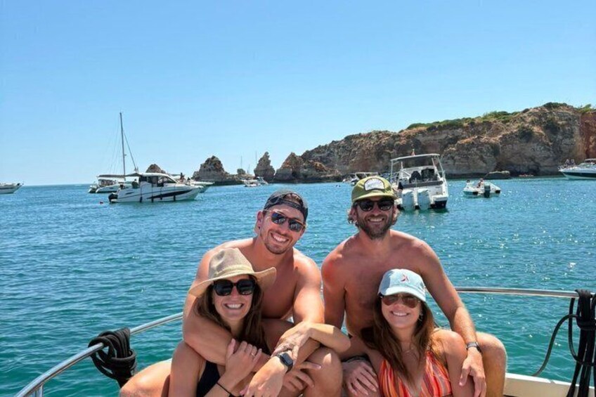 A group of people on a boat with a rocky coastline and boats in the background. 2
