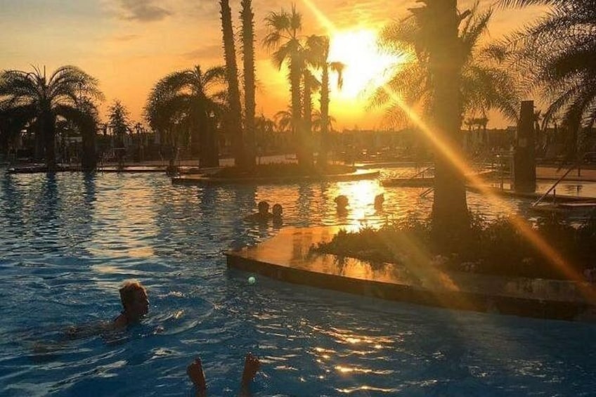 En swimmingpool med palmer och en solnedgång i bakgrunden. 4