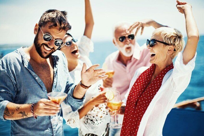 A group of people on a boat, holding drinks, with the ocean in the background. 2