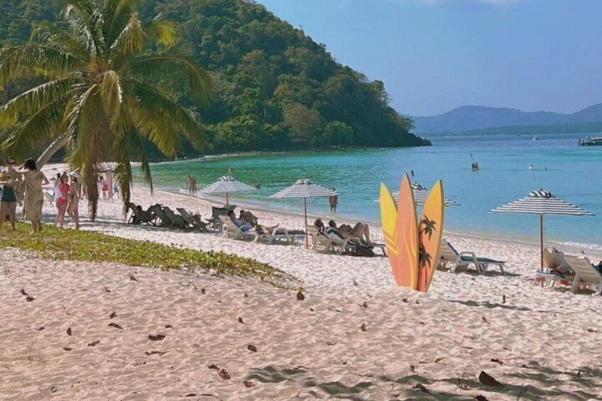 Ein Strand mit Menschen, Palmen und Sonnenschirmen. 2