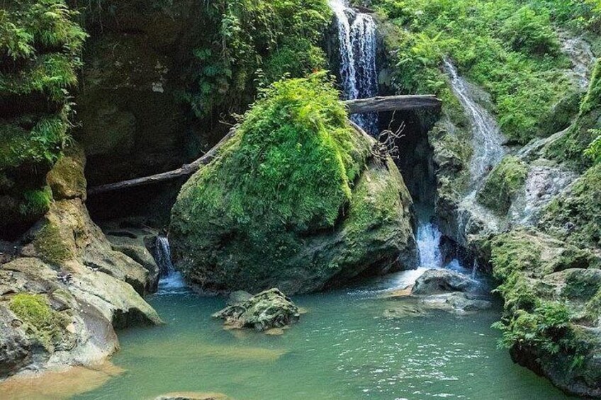 A waterfall cascading over moss-covered rocks into a clear pool. 3
